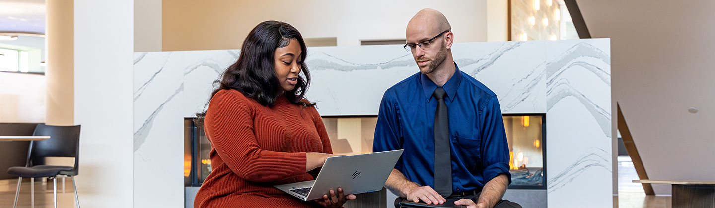 Two people meeting over laptop near fireplace