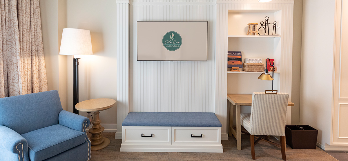 carousel-golf-view-queen-terrace-3-1200x556 Lounge chair, tv hung over a bench, and a desk with chair.