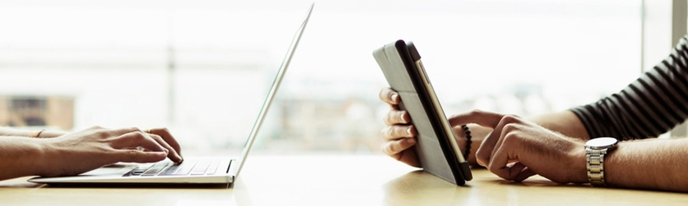 Person typing on laptop another on tablet