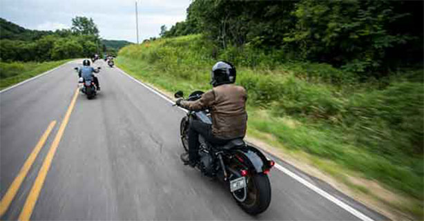 Group of motorcycles riding on a two-lane road.