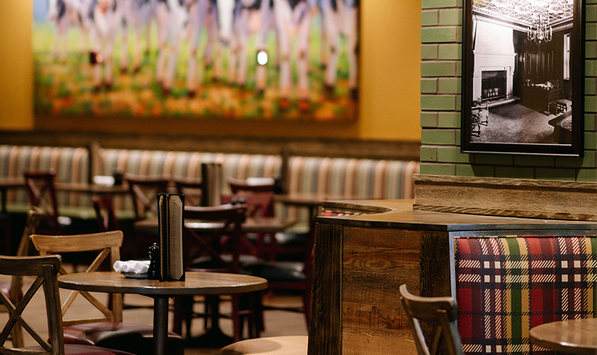 Wood tables and a painting of cows on the wall of the PJ's dining area.