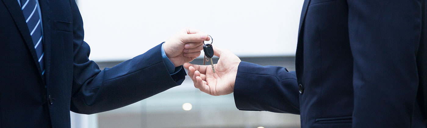 Men in suits exchanging set of keys