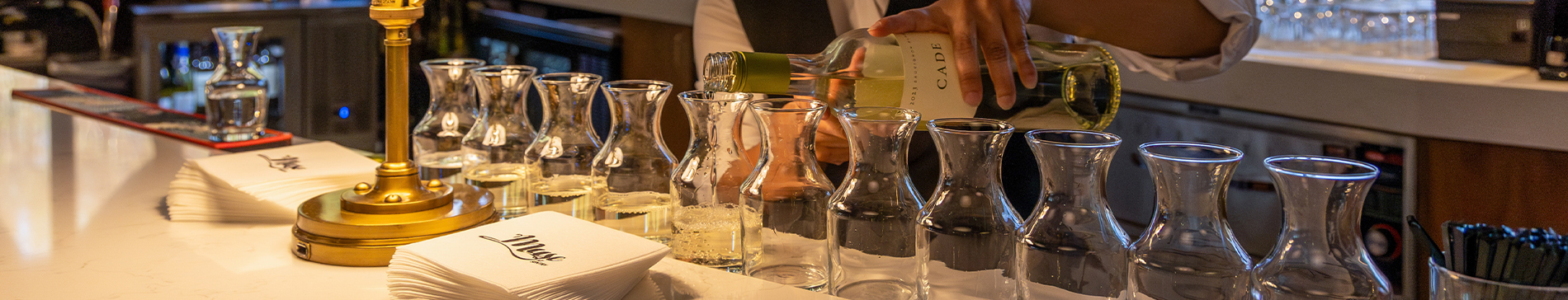 Server pouring wine into small containers on the Muse bar