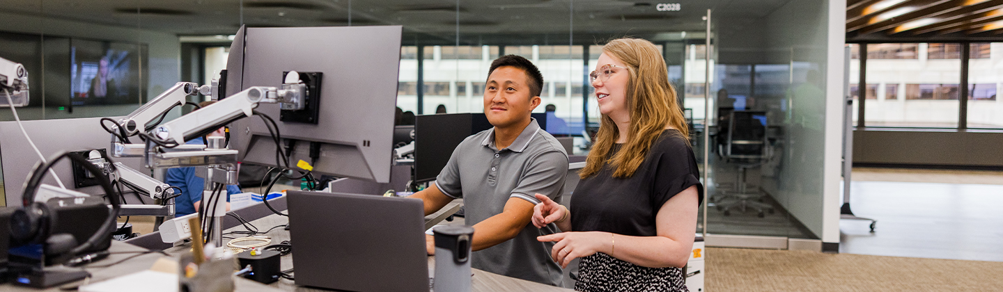 man and woman working together on a computer in an office setting