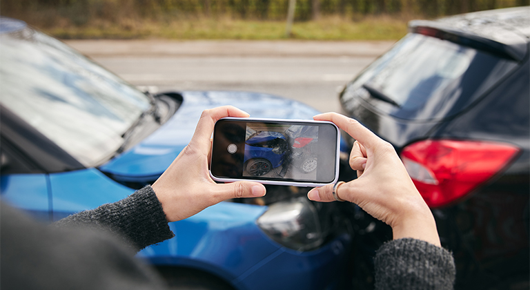 Person taking a photo of damage after a car accident.
