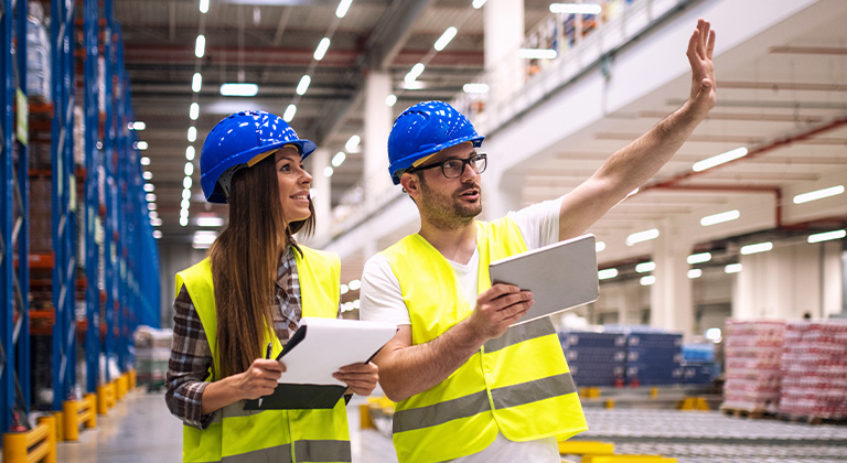 Two people wearing high visibility vest with hard hats on