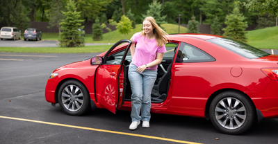 Young woman coming out of car