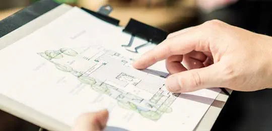 Hands pointing at a property map on a clipboard