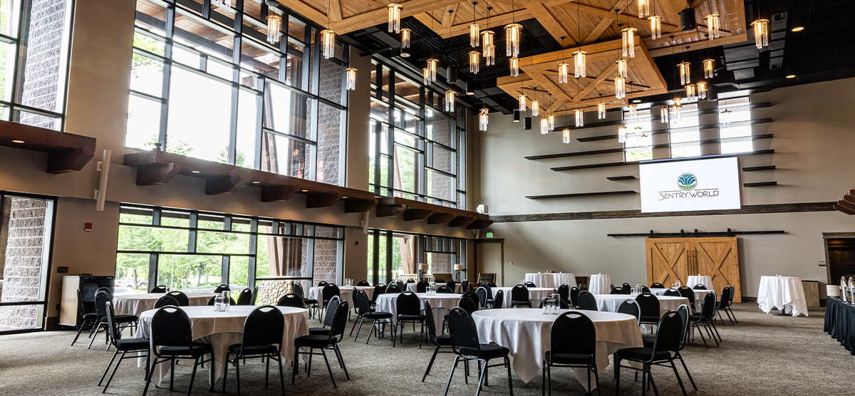 Groups of tables with white clothes set for an event in the Atrium at SentryWorld