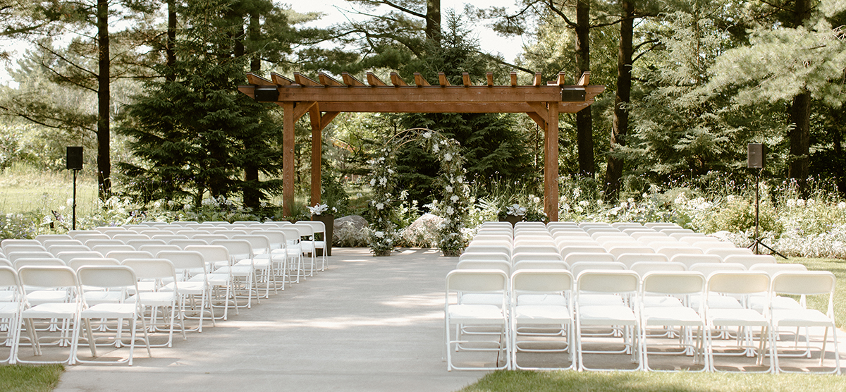 carousel-wedding-venue-pergola-3-1200x556 Pergola set up with white chairs for a wedding.