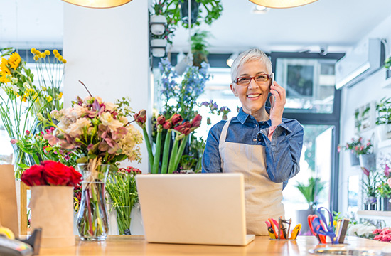 A lady talking on phone while working at a flower shop