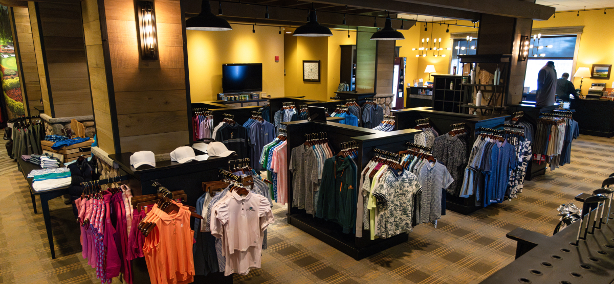 Pro shop area with racks of clothing, clubs, and accessories for sale. 