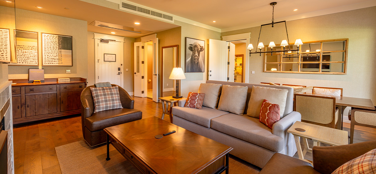 carousel-suite-golf-view-queen-6-1200x556 Suite parlor room with dining room table and sitting area.