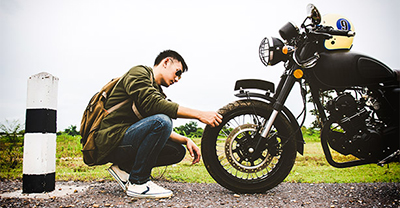 Motorcyclist checking his tire before riding.