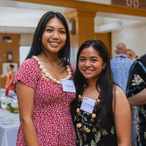 Two scholarship recipients smiling in Hawaiian necklaces