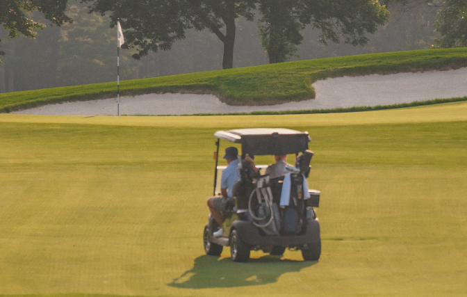 Two golfers driving a golf cart.