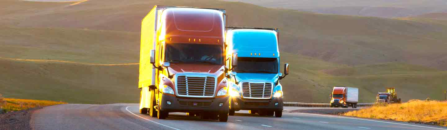 Two trailer trucks driving down highway