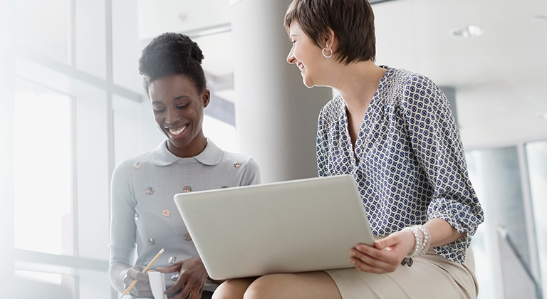 Two business women in meeting smiling one with laptop