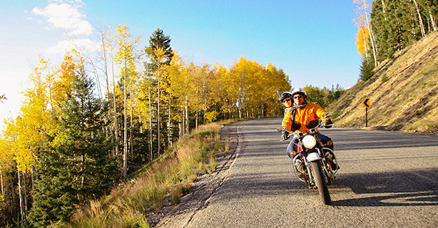 A couple rides motorcycle in bright apparel