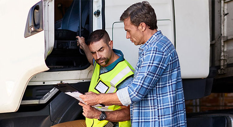 Semi trailer truck driver talking to coworker outside truck