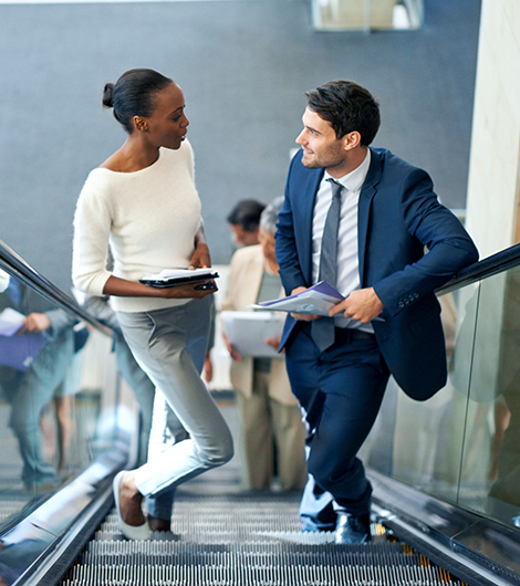 Two business people riding escalator