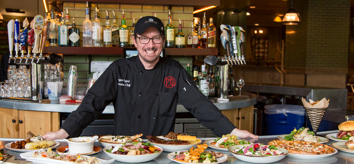 PJ's chef smiling with food laid out on the bar