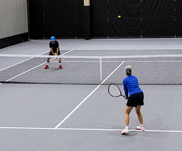 Two people playing tennis in the SentryWorld fieldhouse