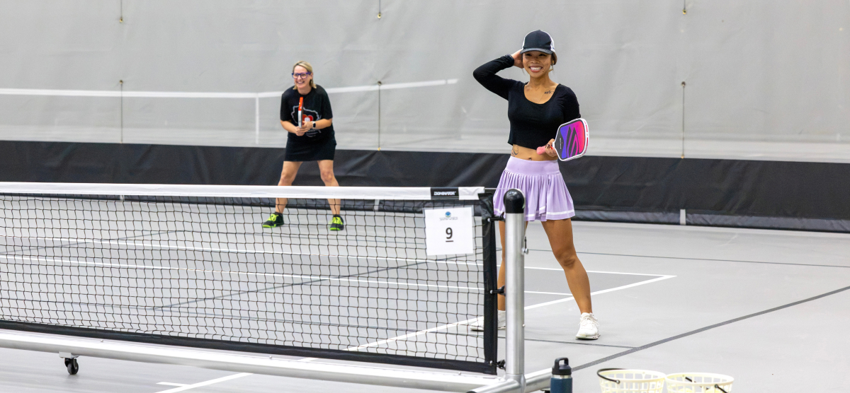Two female pickleball players ready to return.