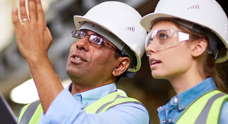 Two people in hard hats surveying