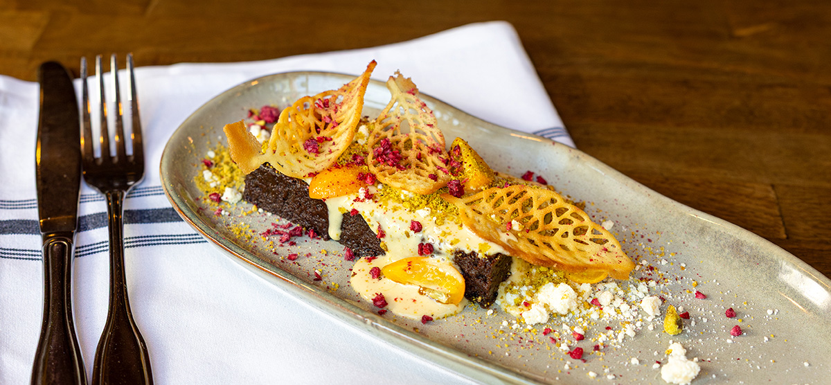 Steam cake with pistachios, kumquats, white chocolate, honey anglaise, and edible fall leaves.