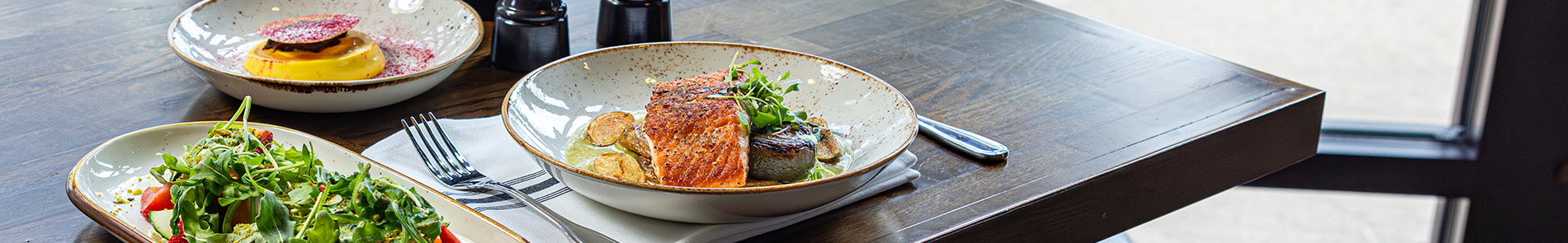 Salad, salmon, and dessert plates on a table. 