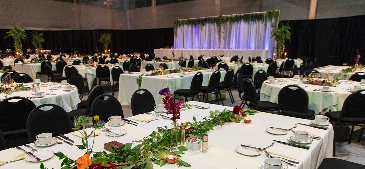 carousel-wedding-venue-fieldhouse-3-1200x556 White tables decorated with flowers for a wedding in the fieldhouse.