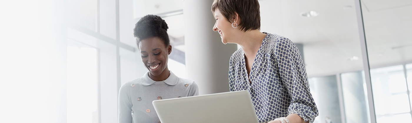 Two business women in meeting smiling one with laptop