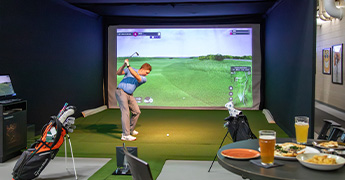 Golfer playing the golf simulator in the SentryWorld fieldhouse