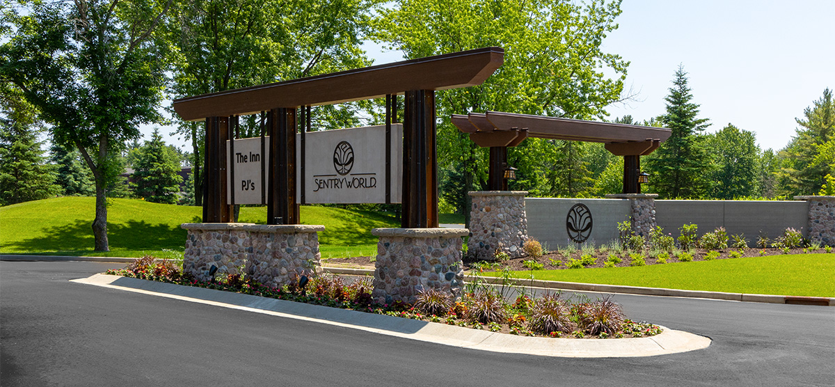 Entrance sign for SentryWorld with stone pillars and wooden beams.