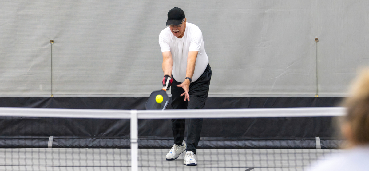 Male pickleball player serves.