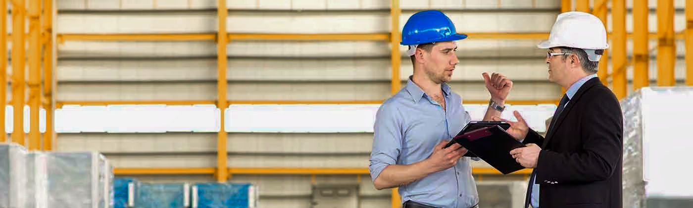 Two people in hard hats on jobsite talking