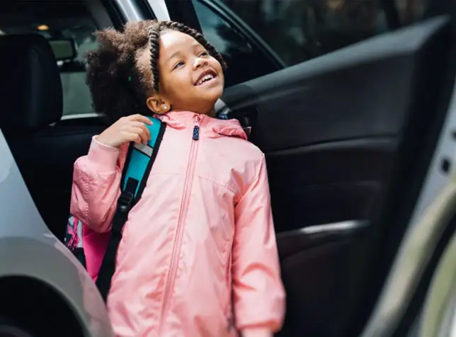 a little girl smiling and exiting the car