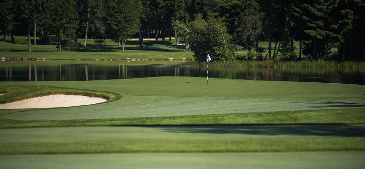 Third hole putting green, sand trap, and water hazard at the SentryWorld golf course