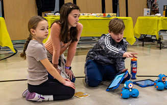 Kids working on tech projects on gymnasium floor