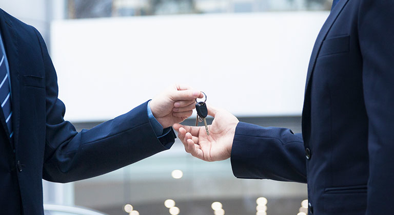 Men in suits exchanging set of keys