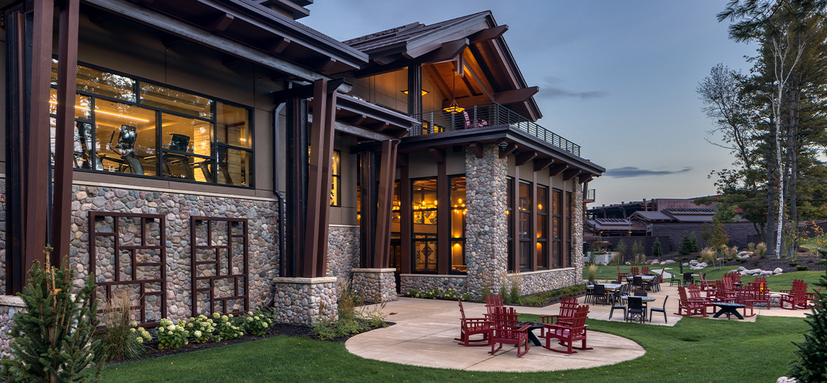 The Inn back exterior at dusk with fitness area and porch lit up. 