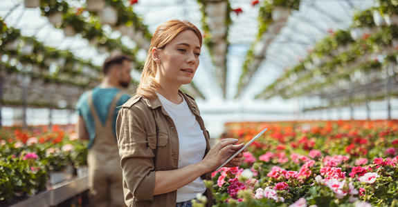 woman on tablet in greenhouse