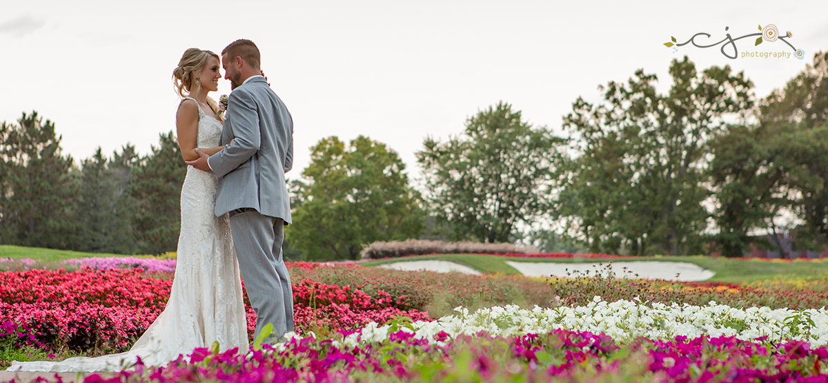 Bride and groom posing in front of the flower hole on the SentryWorld golf course