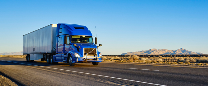 semi truck driving on highway with mountains in background