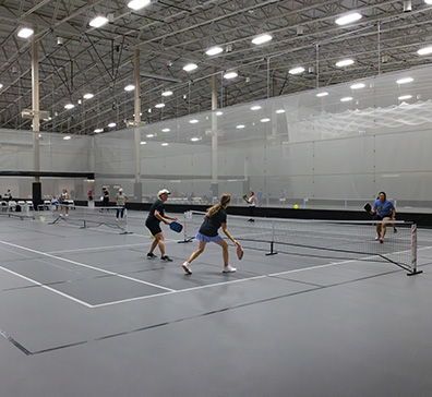Fieldhouse pickleball courts with players playing pickleball. 