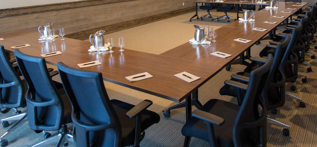 Tables set with notepads, pens, and glasses of water for a meeting