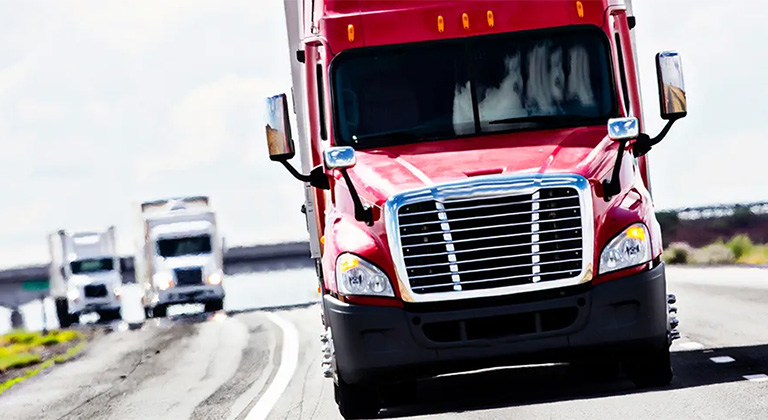 Red semi trailer truck driving down highway