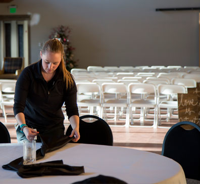 Event worker folding napkins for dining in preparation for a wedding