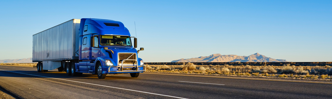 semi truck driving on highway with mountains in background